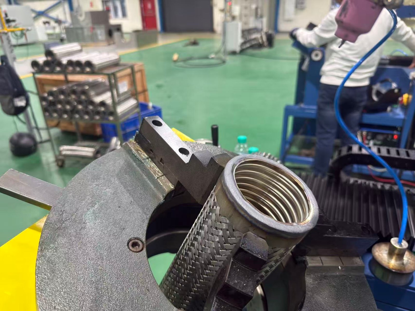 Braided metal hose positioned in a welding fixture for automated hose fitting production
