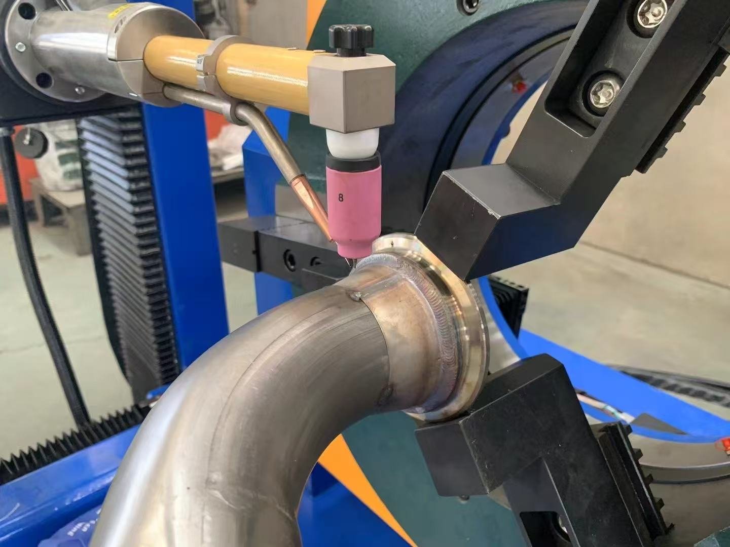 Stationary TIG torch welding a circumferential coupling joint on a bent tube